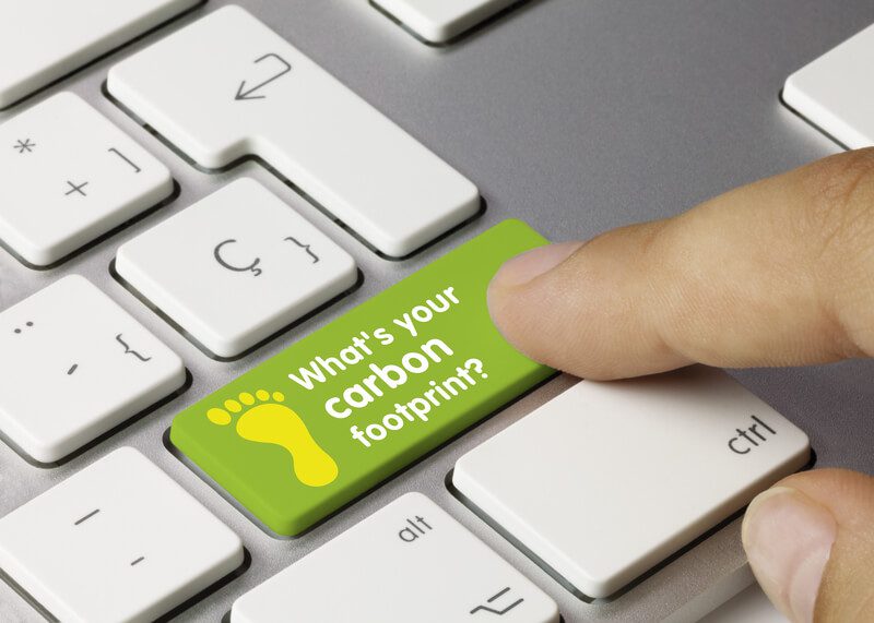 What`s your carbon footprint? Written on Green Key of Metallic Keyboard. Finger pressing key
